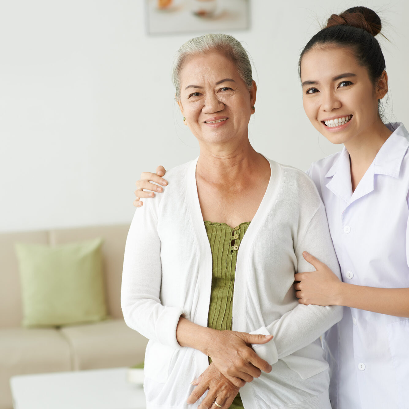 Young nurse and senior woman looking at camera with smiles